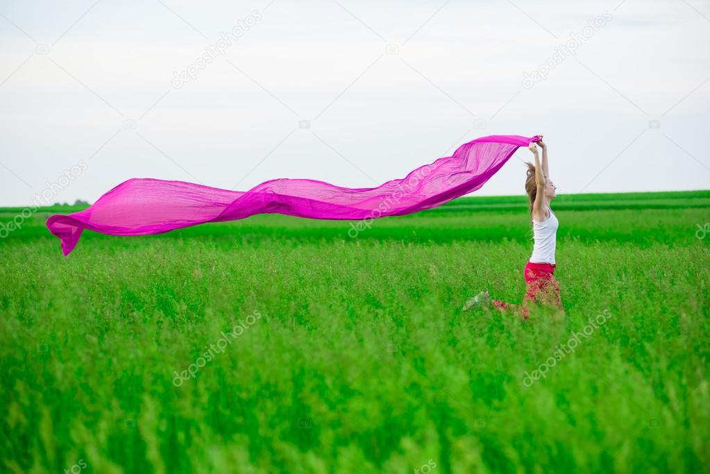 Young lady runing with tissue in green field. Woman and scarf.