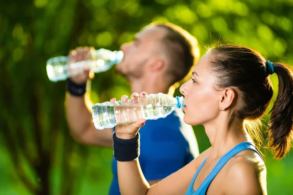 Mężczyzna i kobieta wody pitnej z butelki po treningu sportowego fitness — Zdjęcie stockowe