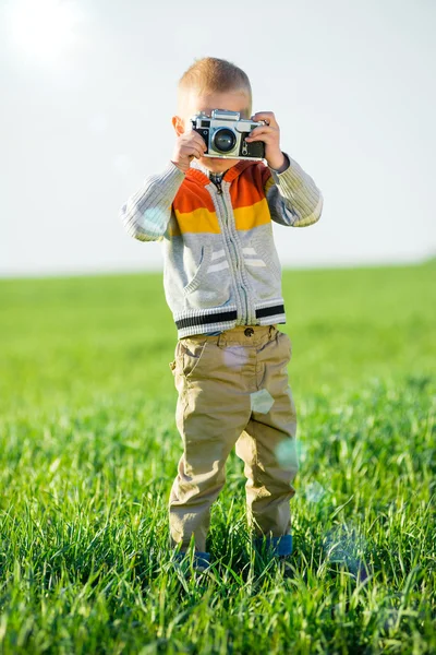 Kleiner Junge mit einer alten Kamera, die draußen schießt. — Stockfoto