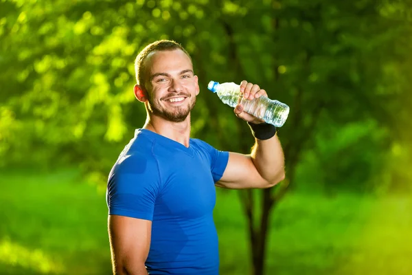 Athletic mogen man dricksvatten från en flaska — Stockfoto