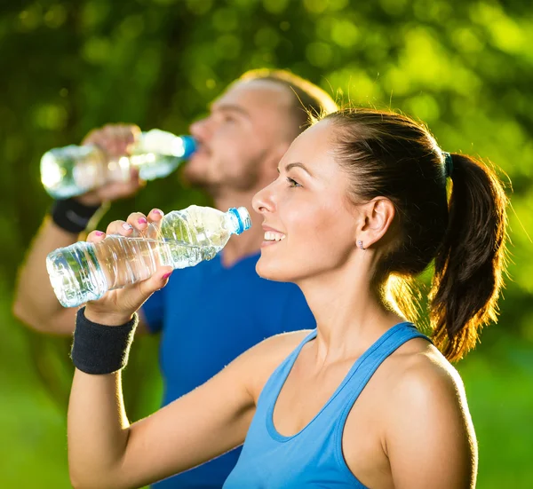 Hombre y mujer bebiendo agua de la botella después del ejercicio deportivo de fitness —  Fotos de Stock