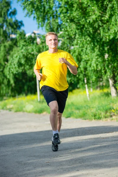 Sporty man jogging in city street park. Outdoor fitness. — Stock Photo, Image