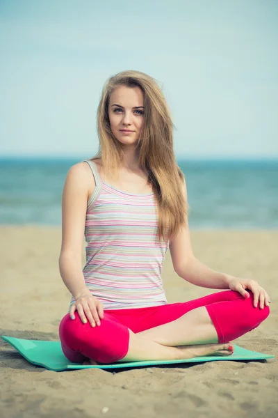 Jovencita practicando yoga. Entrenamiento cerca de la costa del mar . — Foto de Stock