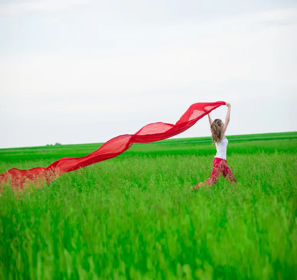 Jeune femme courant avec des tissus dans un champ vert. Femme avec écharpe . — Photo
