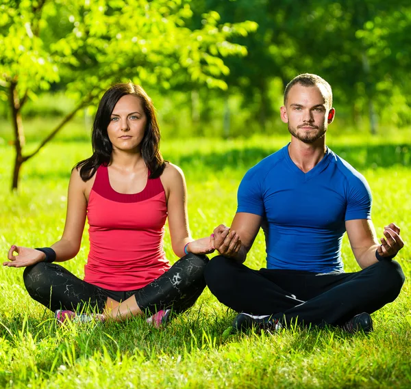 Genç adam ve kadın güneşli yaz parkta yoga yaparken — Stok fotoğraf