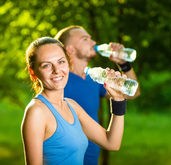 Hombre y mujer bebiendo agua de la botella después del ejercicio deportivo de fitness — Foto de Stock