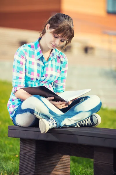 Studentin mit Textbuch auf Bank. Sommer-Campus-Park. — Stockfoto