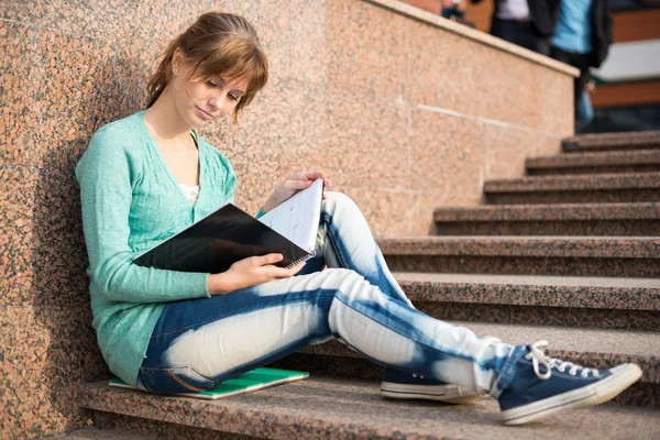 Meisje, zittend op een trap en lezen van de opmerking — Stockfoto