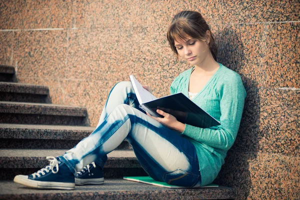 Meisje, zittend op een trap en lezen van de opmerking — Stockfoto