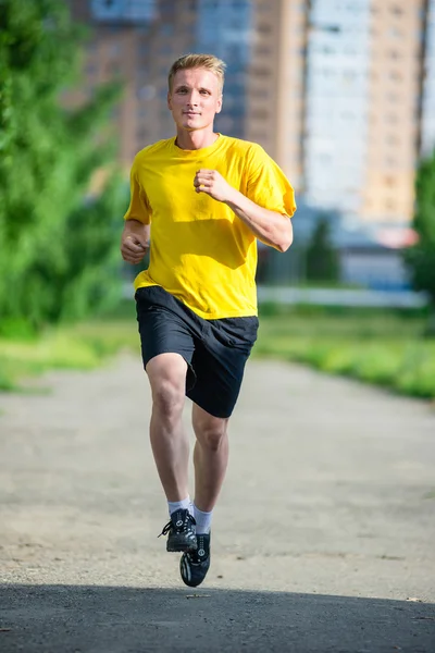 Sporty man jogging in city street park. Outdoor fitness. — Stock Photo, Image