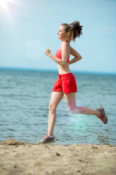 Ung dam kör på solig sommar sand stranden. Träning. JOG — Stockfoto