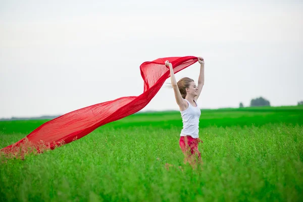Jovem a correr com lenços no campo verde. Mulher com cachecol . — Fotografia de Stock