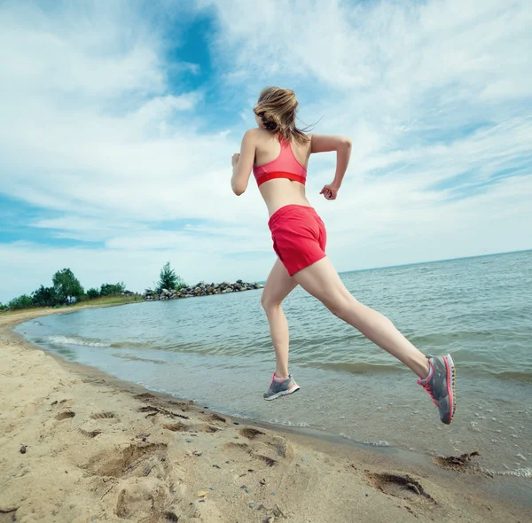 Jeune femme courant à la plage de sable ensoleillée d'été. Entraînement. Jogging Image En Vente