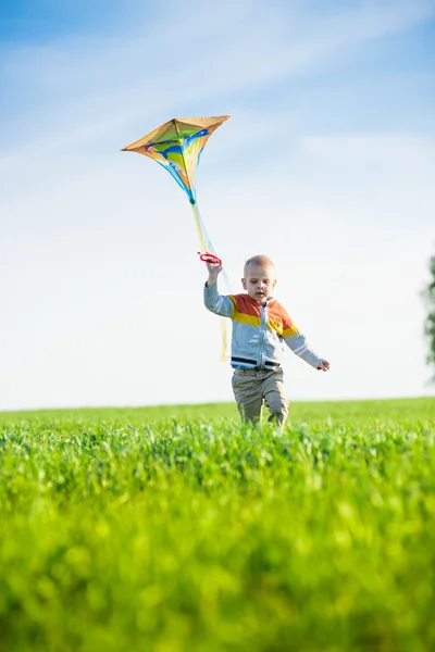 Giovane ragazzo che gioca con il suo aquilone in un campo verde . — Foto Stock