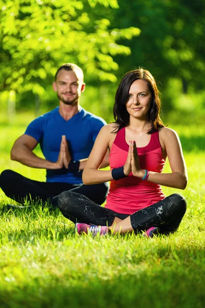 Jonge man en vrouw doen yoga in het zonnige zomer park — Stockfoto