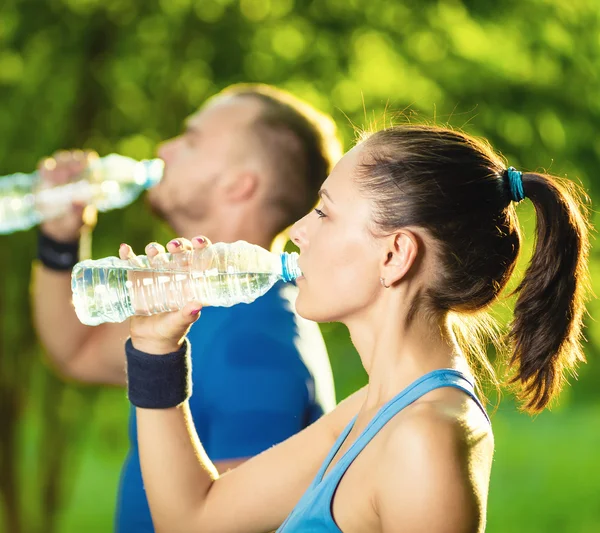 Hombre y mujer bebiendo agua de la botella después del ejercicio deportivo de fitness — Foto de Stock