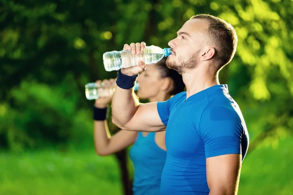 Homme et femme buvant de l'eau de bouteille après l'exercice sportif de remise en forme — Photo