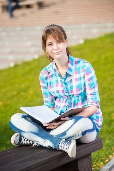 Studentessa con copybook su panchina. Estate campus park . — Foto Stock