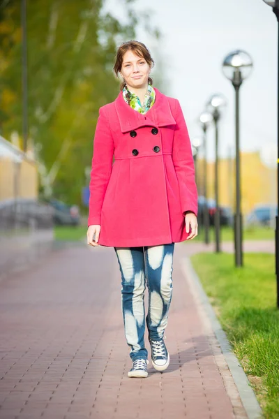 Beautiful woman in red coat walking autumn street.