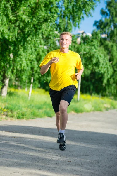 Sporty man jogging in city street park. Outdoor fitness. — Stock Photo, Image