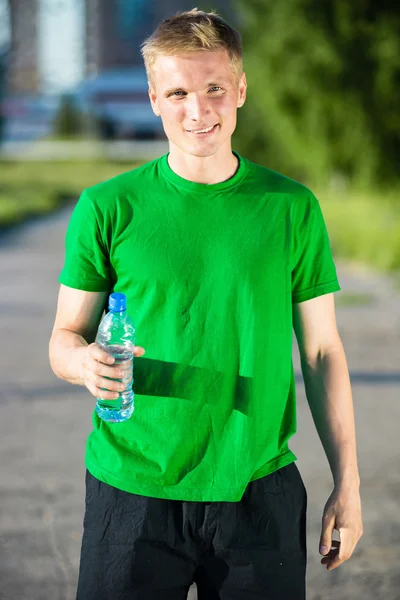 Müder Mann trinkt nach Fitness Wasser aus Plastikflasche — Stockfoto