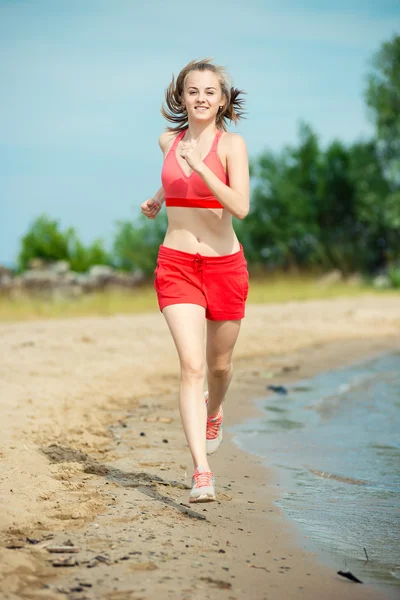 年轻的女士在阳光灿烂的夏天砂沙滩上运行。锻炼。慢跑 — 图库照片