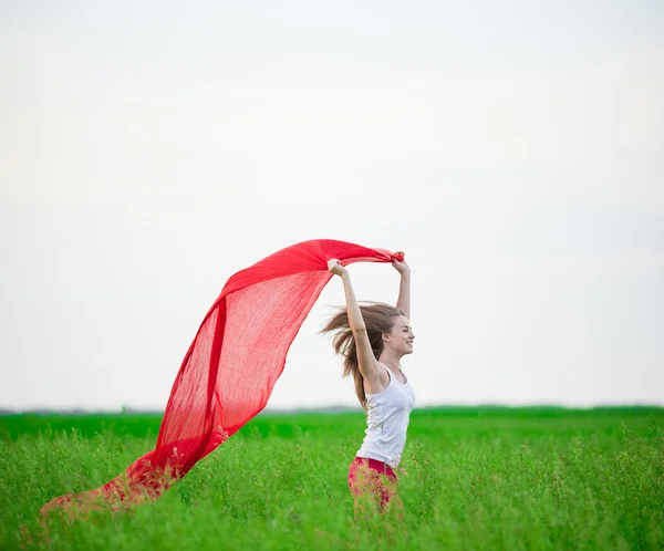 Jonge dame runing met weefsel in groene veld. Vrouw met sjaal. — Stockfoto