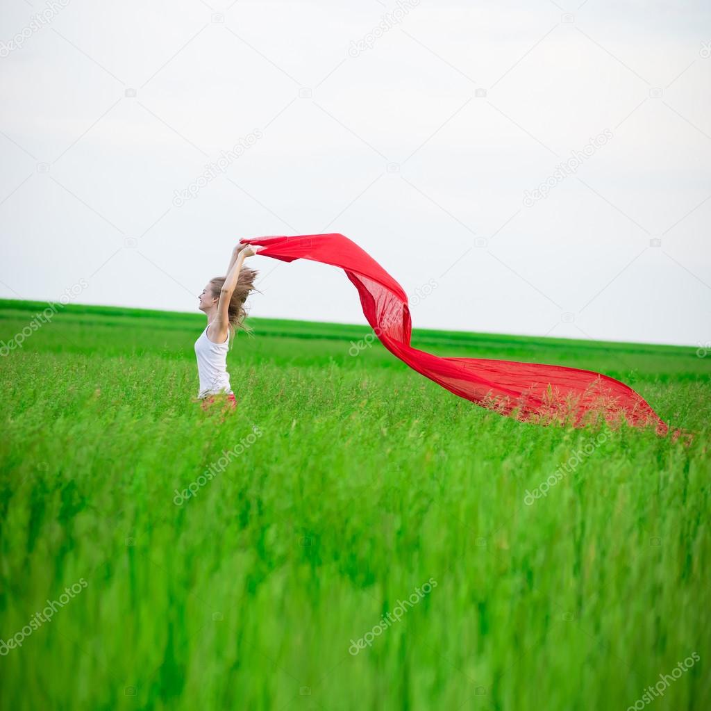 Young lady runing with tissue in green field. Woman with scarf.