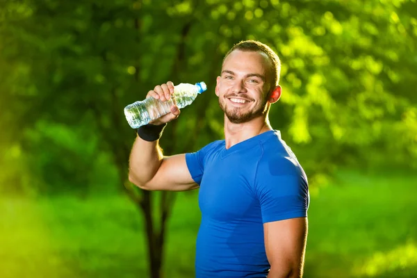 Athletic mogen man dricksvatten från en flaska — Stockfoto