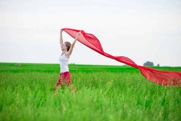 Young lady runing with tissue in green field. Woman with scarf. — Stock Photo, Image