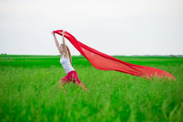 Jonge dame runing met weefsel in groene veld. Vrouw met sjaal. — Stockfoto