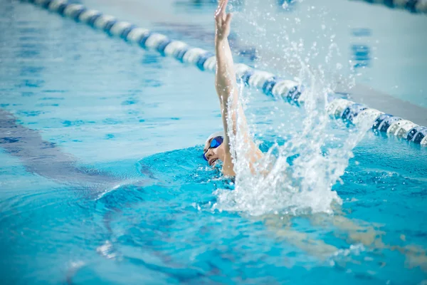 Молодая девушка в очках, плавающая в стиле фронтального инсульта — стоковое фото