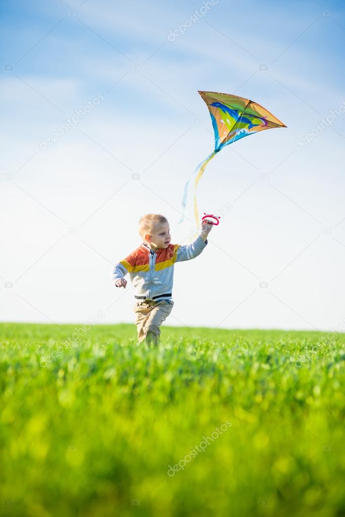 Young boy playing with his kite in a green field.