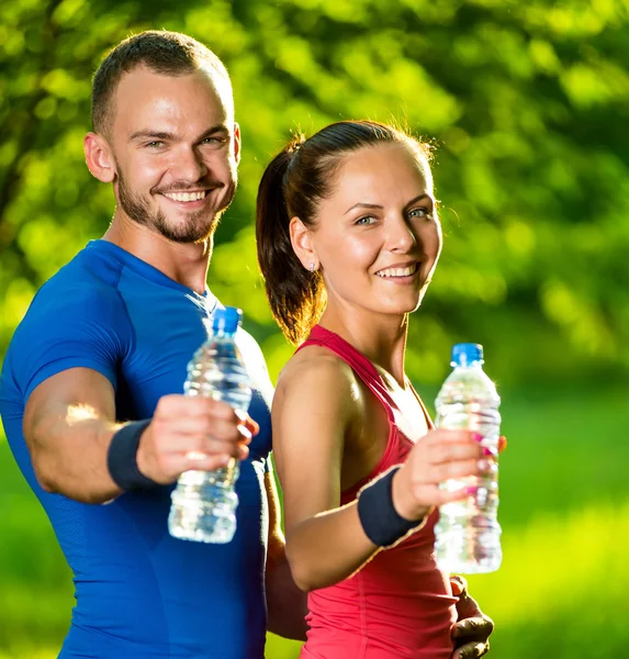 Hombre y mujer bebiendo agua de la botella después del ejercicio deportivo de fitness —  Fotos de Stock