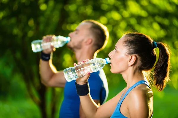 Hombre y mujer bebiendo agua de la botella después del ejercicio deportivo de fitness — Foto de Stock