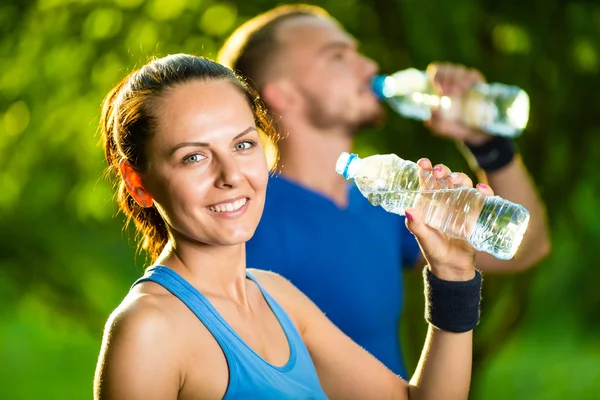 Mężczyzna i kobieta wody pitnej z butelki po treningu sportowego fitness — Zdjęcie stockowe