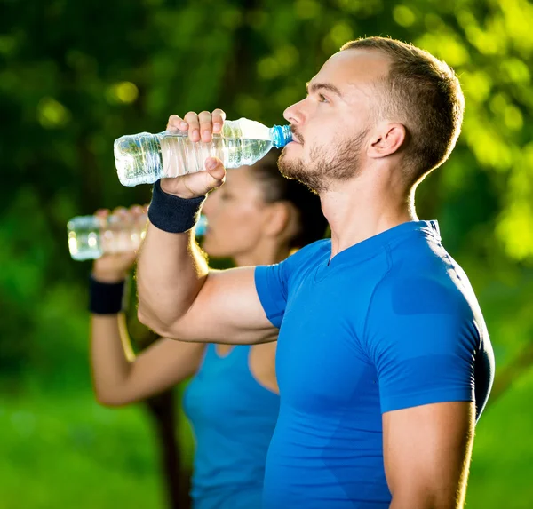 Man and woman drinking water from bottle after fitness sport exercise — Stock Photo, Image