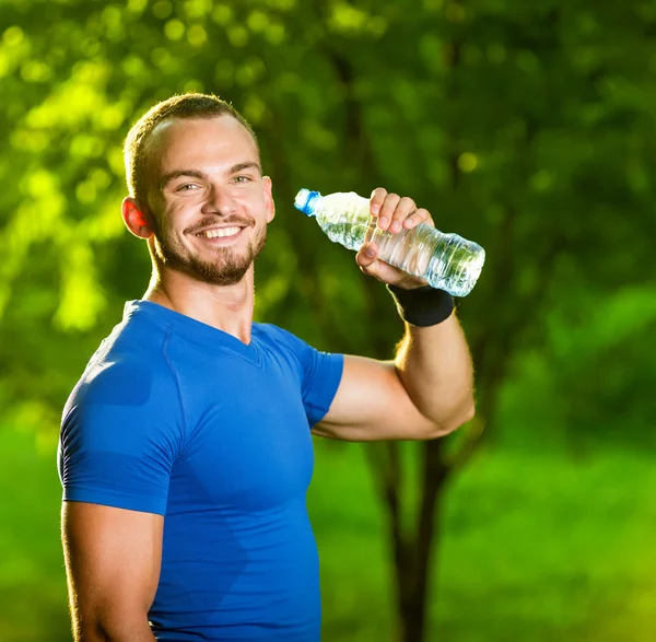 Atletik olgun adam içme suyu bir şişe — Stok fotoğraf