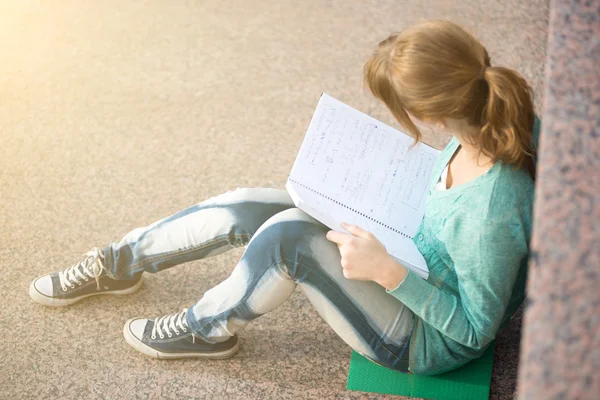 Girl sitting on stairs and reading note — Stock Photo, Image