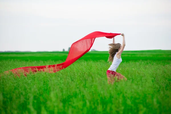 Giovane donna che corre con tessuto in campo verde. Donna con sciarpa . — Foto Stock