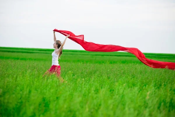 Young lady runing with tissue in green field. Woman with scarf. — Stock Photo, Image