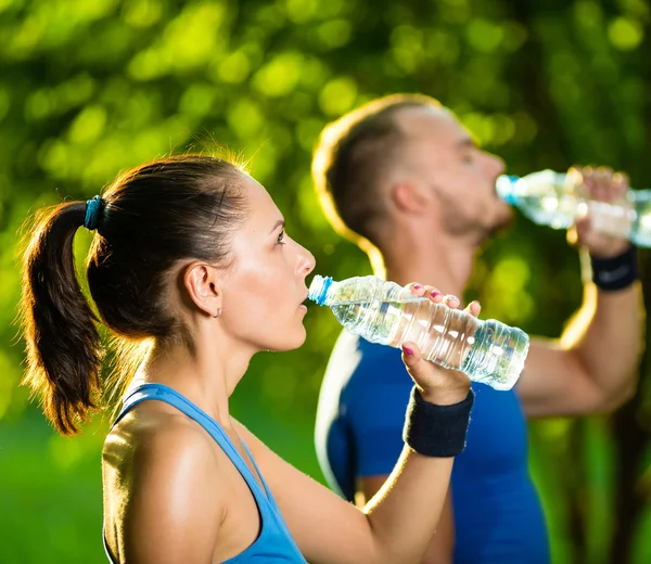 Hombre y mujer bebiendo agua de la botella después del ejercicio deportivo de fitness —  Fotos de Stock