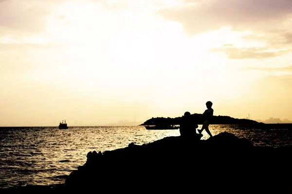 Silhuetas na praia ao pôr do sol — Fotografia de Stock