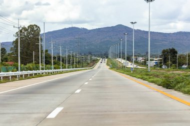 Kırsalda mavi bulutlar ve gökyüzü arkaplanı olan boş bir otoyol.