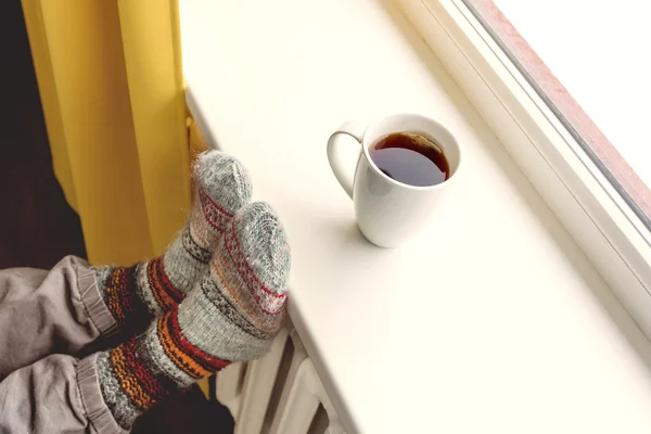Warming by the radiator and drinking hot tea — Stock Photo, Image