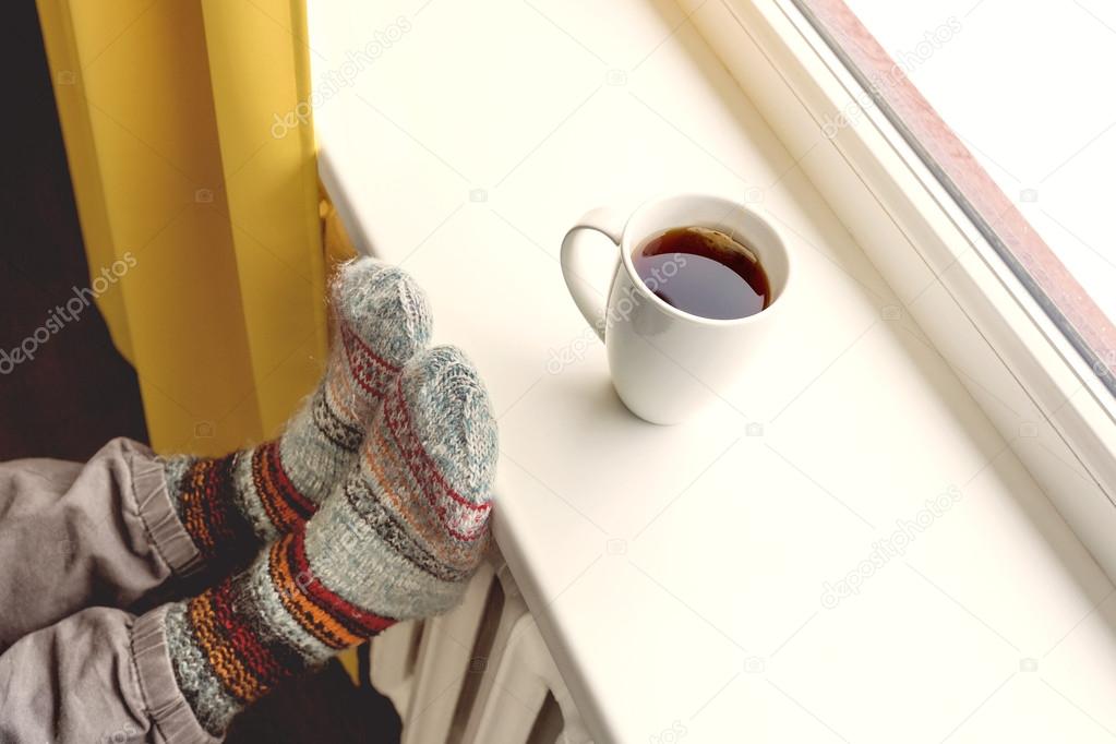 warming by the radiator and drinking hot tea