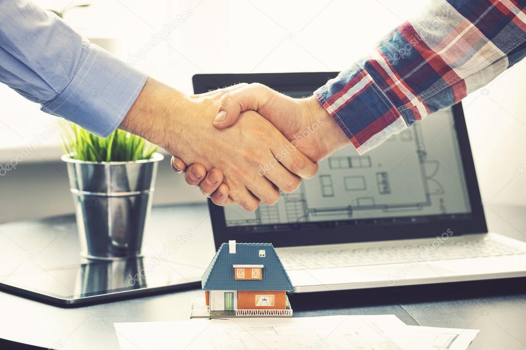 real estate agent shaking hands with customer after deal at offi