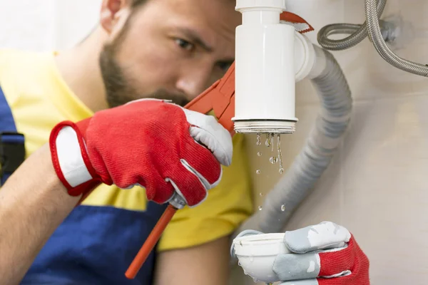 Loodgieter tot vaststelling van de sifon van de wasbak in een badkamer of keuken — Stockfoto