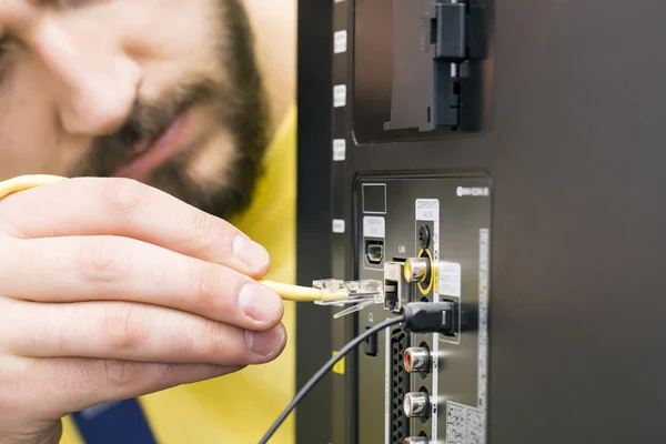 Man connects internet cable to the TV — Stock Photo, Image