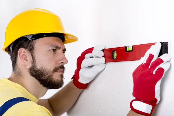 Bouwvakker controleer het niveau op de muur — Stockfoto